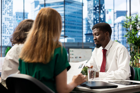 HR professionals negotiating job offers and salary packages with candidate after successful conversation. HR coworkers talking with applicant, analyzing resume, cover letter and background informationの写真素材