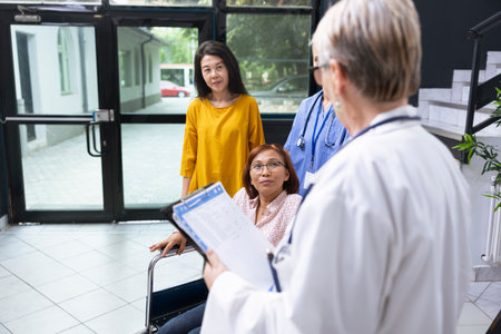 Wheelchair user discussing with medic at routine checkup at the clinic, offering guidance and assistance while discussing medical condition care for physical disability. Health check.の写真素材