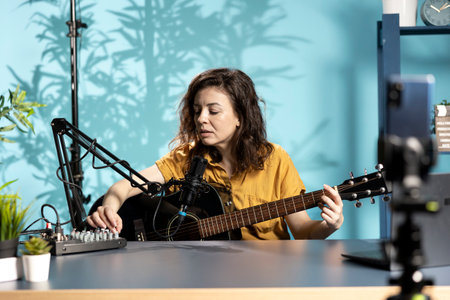 Talented composer doing songwriting, playing music on guitar during livestream with audience online. Musician using musical instrument, recording music video, having fun doing concert for fansの写真素材