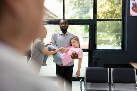 Panic sets in as father is carrying his unconscious little child in lobby, leading to quick intervention from doctor and nurse during emergency. Urgent medical needs and consultation.の写真素材