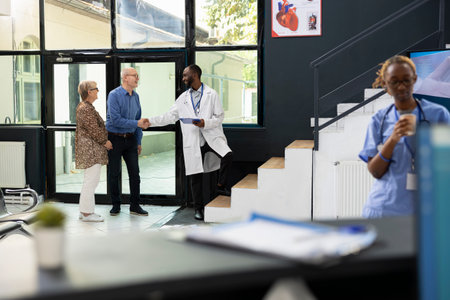 Old male patient receives treatment plan recommendations from black doctor during appointment in the lobby, discussing wellness strategies and prevention methods in a modern clinic.の写真素材
