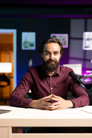 Portrait of influencer in home studio using professional microphone to record live broadcast for online streaming platforms, talking with fans. Smiling media star hosts q and a session with viewersの写真素材