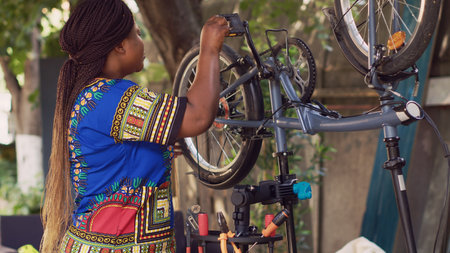 Dedicated female cyclist arranging bicycle tools from specialized toolbox for maintenance and repairs. African american woman assembling professional equipment on bike repair-stand.の写真素材