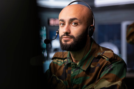 Military specialist reporting battlefield information to army decision makers using headset microphone. Middle Eastern dispatcher talking with generals on call, giving enemy coordinatesの写真素材