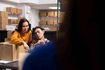 Asian workers team packing boxes in the storage room for small business, ensuring order processing and product handling. People working hard on developing the local brand in warehouse.の写真素材
