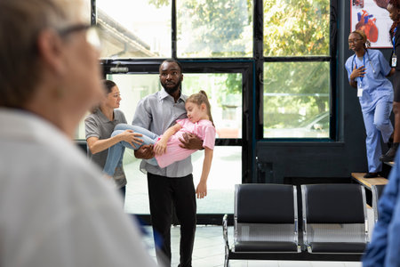 Girl fainted and her african american father is carrying her in the hospital, waiting for immediate care response from the medical team. Clinical situation marked by urgency and family concern.の写真素材