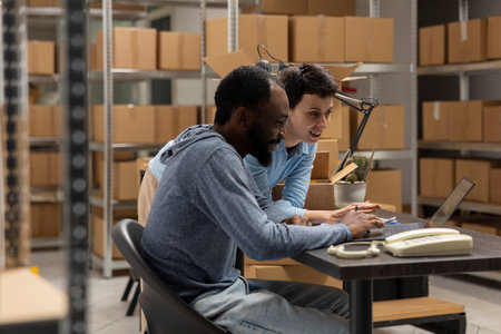 Multiethnic team of employees work in a local shipping depot, coordinating product handling and warehouse operations to help a small business grow. Distribution hub logistics.の写真素材