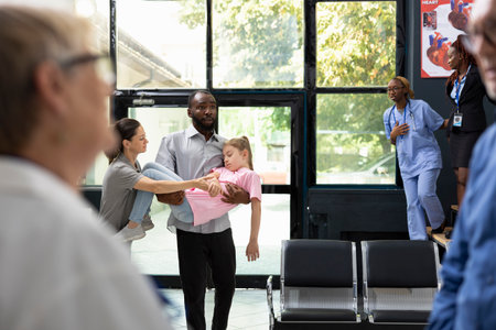 Young kid faints in her father arms with worried mother by her side, as african american team provides first aid and assistance during pediatric emergency and family health scare.の写真素材