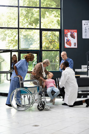 Family emergency unfolds as young niece collapses in hospital lobby, with elderly grandparents seeking diagnosis and treatment from healthcare professionals during critical pediatric situation.の写真素材