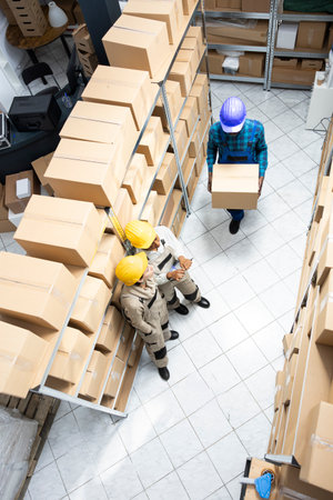 Multiethnic staff in safety gear managing merchandise and logistics operations. Warehouse environment designed for effective inventory and transportation, distribution management.の写真素材