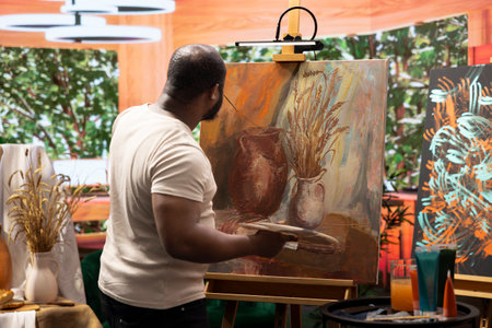 In a creative workshop, artist mixes pigments to achieve the perfect dye shade. Using professional art supplies to create a beautiful masterpiece on canvas, quality time in atelier.の写真素材