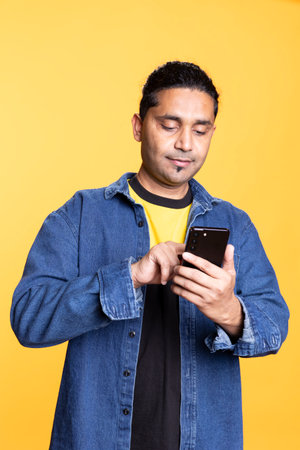 Indian man adding payment method on online website with his card, delighted to take advantage of promotions in the studio. Young person thrilled to do internet shopping, typing credit card data.の写真素材