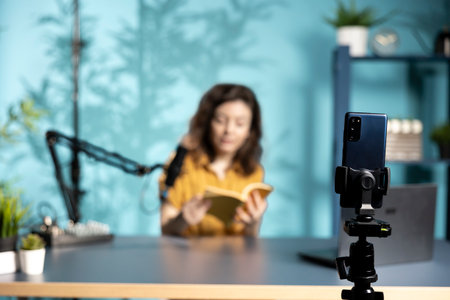 Close up of phone used by woman being sponsored by partnering publisher to do new book unboxing content. Focus on smartphone used by influencer to do new author novel product placementの写真素材