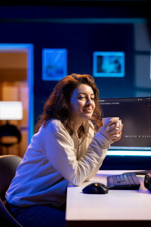 Smiling IT admin drinking coffee while fixing vulnerabilities in software enabling hackers to...