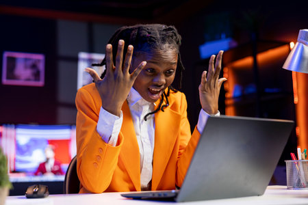 Angry freelancer at desk yelling while working from home in apartment office, upset by error on laptop screen. Stressed woman raging, having burnout while doing tasks on notebookの写真素材