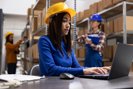 Asian female worker ensures shipping logistics in a small scale depot. Preparing taped boxes at the shipping area to support efficient small business e commerce operations and delivery.の写真素材