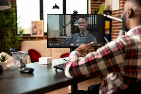 Professional african american man in video conference call, working remotely from home. Virtual business collaboration between black male colleagues on company goals and marketing strategy.の写真素材