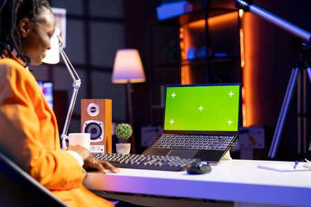 Teleworker in living room office using chroma key laptop to answer emails from business associates. Remote employee typing on isolated screen device keyboard, solving tasks in apartmentの写真素材