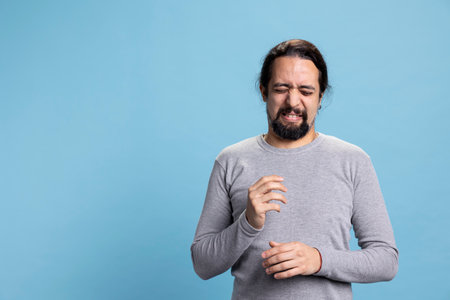 Crazy silly person acting disgusted and unpleasant against blue background, gross discontent guy making a grimace and sticking tongue out. Disgusted annoyed man dissatisfied with something.の写真素材
