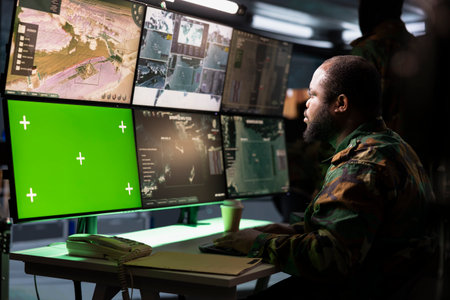 Military early warning systems operator monitoring enemy aerial attacks using green screen satellite equipment. Army soldier in headquarters maintains air space superiority with chroma key radarの写真素材
