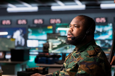 Military dispatcher using headphones microphone, offering information to commanders fighting on front lines. Army specialist providing intel for troops in base of operationsの写真素材