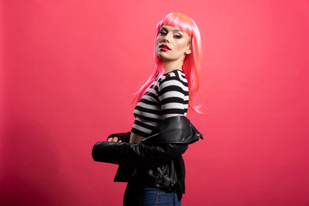 Young glamourous woman with long straight hair and bold makeup, wearing stylish clothes. Fashion model turns slightly and holds strong pose with sharp look at camera in studio.の写真素材