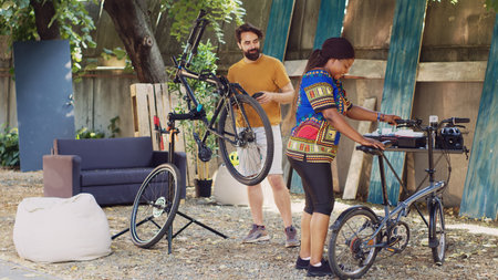 Professional equipment encircling home yard where multiethnic couple is rectifying their bicycles. Black woman and caucasian man are systematically carrying out their routine bike maintenance tasks.の写真素材