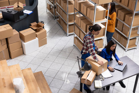 Local brand supply room staff work at distribution hub for order processing and hand packing merchandise. Ensuring local shipping and in house logistics operations for retail fulfillment.の写真素材