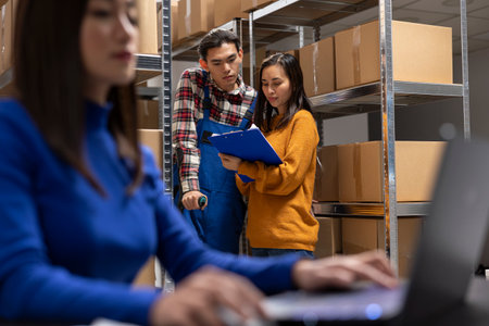 Asian staff member with reduced mobility on crutches prepares parcels in a storage room depot. Team managing in house logistics, order processing and small scale retail delivery.の写真素材