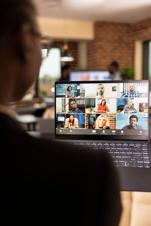 African American professional collaborating online with remote colleagues during videoconference. Black female financial advisor using laptop, attending a virtual meeting with startup company team.の写真素材