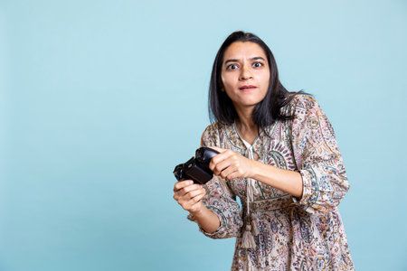 Happy indian woman entertained by video games on her console, enjoying leisure time. Player enjoying...