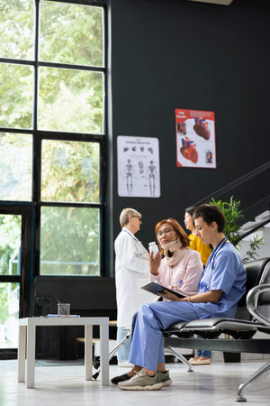 Medical assistant and asian woman discuss treatment plan and solutions for healing process after fracture. Hospital staff offering support with physiotherapy and painkillers during recovery.の写真素材