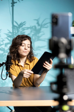 Content creator analyzing newly released gaming tablet received from sponsor, doing honest review for online streaming channel. Media star reviewing digital device from partnering brandの写真素材