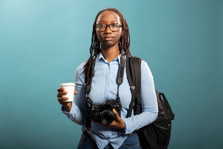 Young woman in suspenders and blue shirts, holding her camera with professionalism and creativity in...