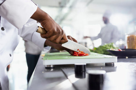 Culinary professional cutting a red bell pepper and preparing fresh ingredients for a gourmet dish....