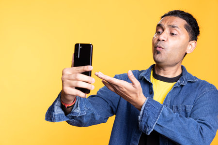 Indian casual person calling his friends on remote teleconference call, feeling confident with his...