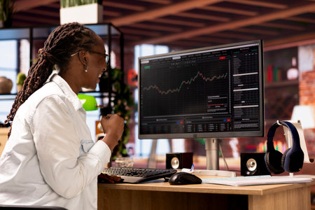 Happy day trader gaining money by selling stocks after browsing through documents to learn how to...