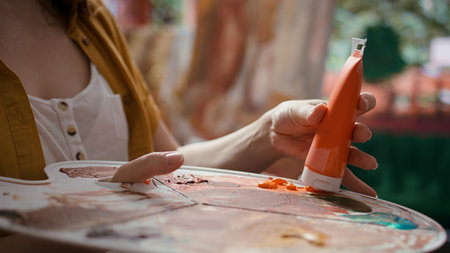 Woman with talent painting a rustic masterpiece and using fabric to clean her brush after changing...