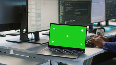 Employees using green screen laptop, working in server farm to optimize it for data processing...