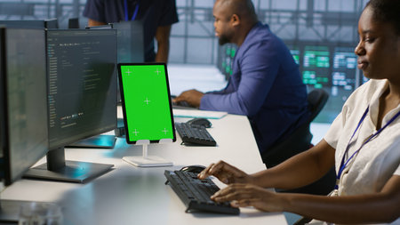 Admin using isolated screen tablet, working in server farm to optimize it for data processing...