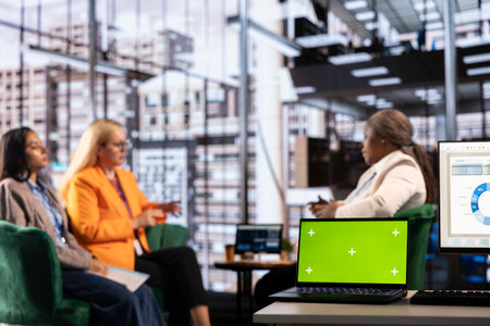 Multiethnic businesswomen working next to isolated green screen, solving their daily tasks for the...