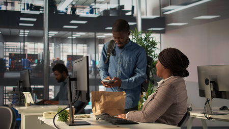 Businesswoman engages with delivery employee highlighting food delivery services in a modern office....
