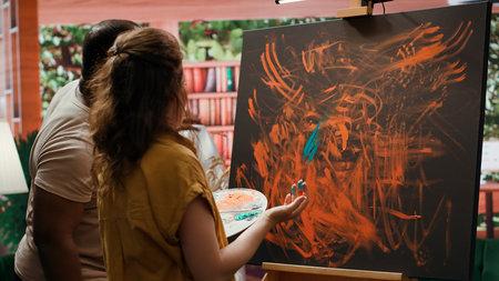 Talented artist and her apprentice engage in finger painting hobby in art and craft workshop, using...