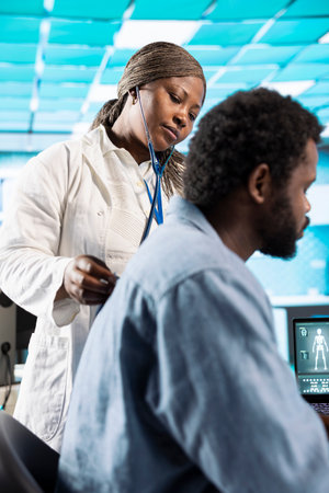 African american medic uses a stethoscope to consult young man with illness, doing an examination...