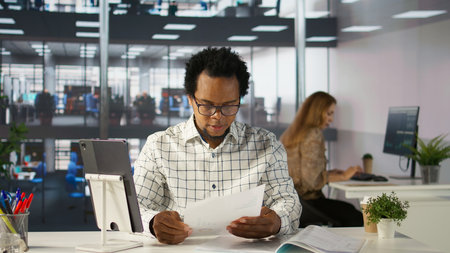 Confident businessman at his office desk working on report writing, financial planning and deadline...