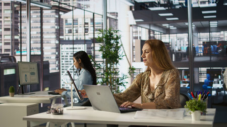 Professional manager at a multinational company works on laptop to track project progress and...
