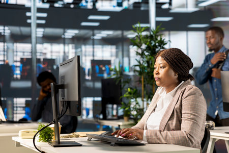 Confident businesswoman at her office desk working on report writing and answering emails,...