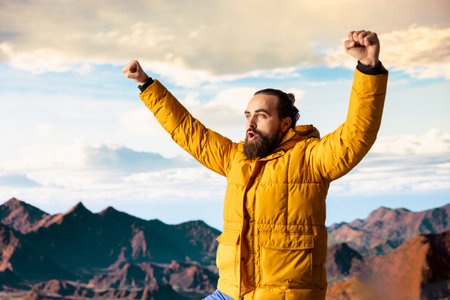 Satisfied adventure seeker stands at the top a towering mountain, taking in the epic view and...