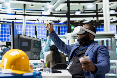 Photovoltaics factory engineer designing on CAD software with VR headset, working in solar panels manufacturing plant. Black technician inspecting assembly lines in virtual reality.の写真素材