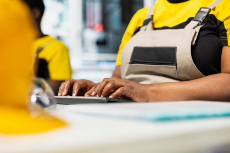 African american technician manages data from solar machinery on computer, working in a solar panel...